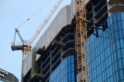 Close-up of a crane building a glass and steel skyscraper.