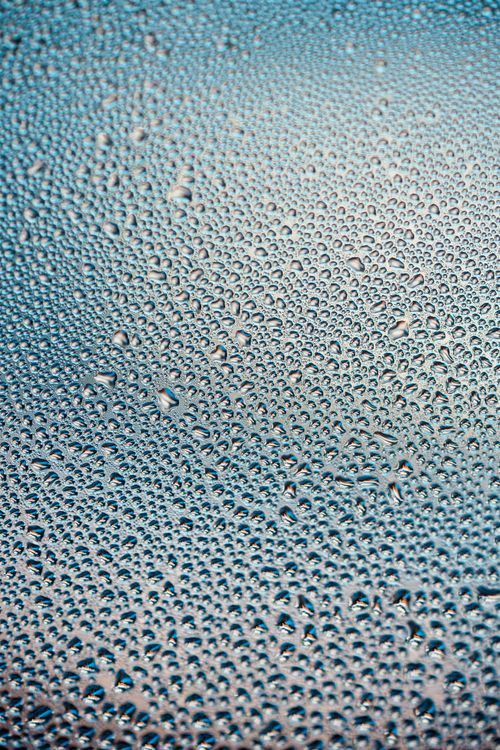 Free Macro photograph showing tiny water droplets creating a texture on a smooth blue surface. Stock Photo