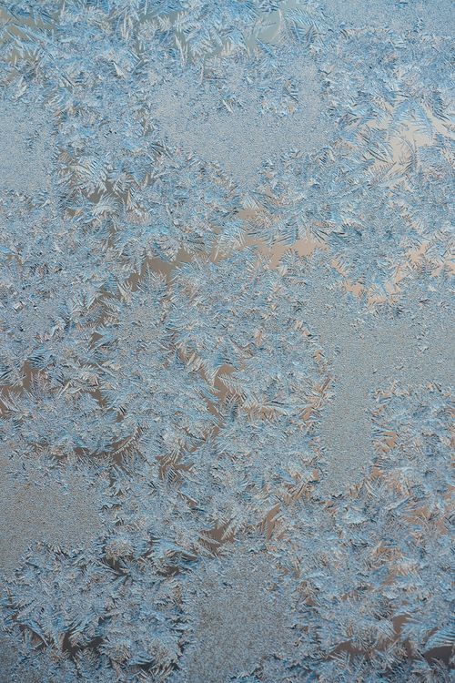 Free Close-up of beautiful ice crystals forming intricate frost patterns on window glass. Stock Photo