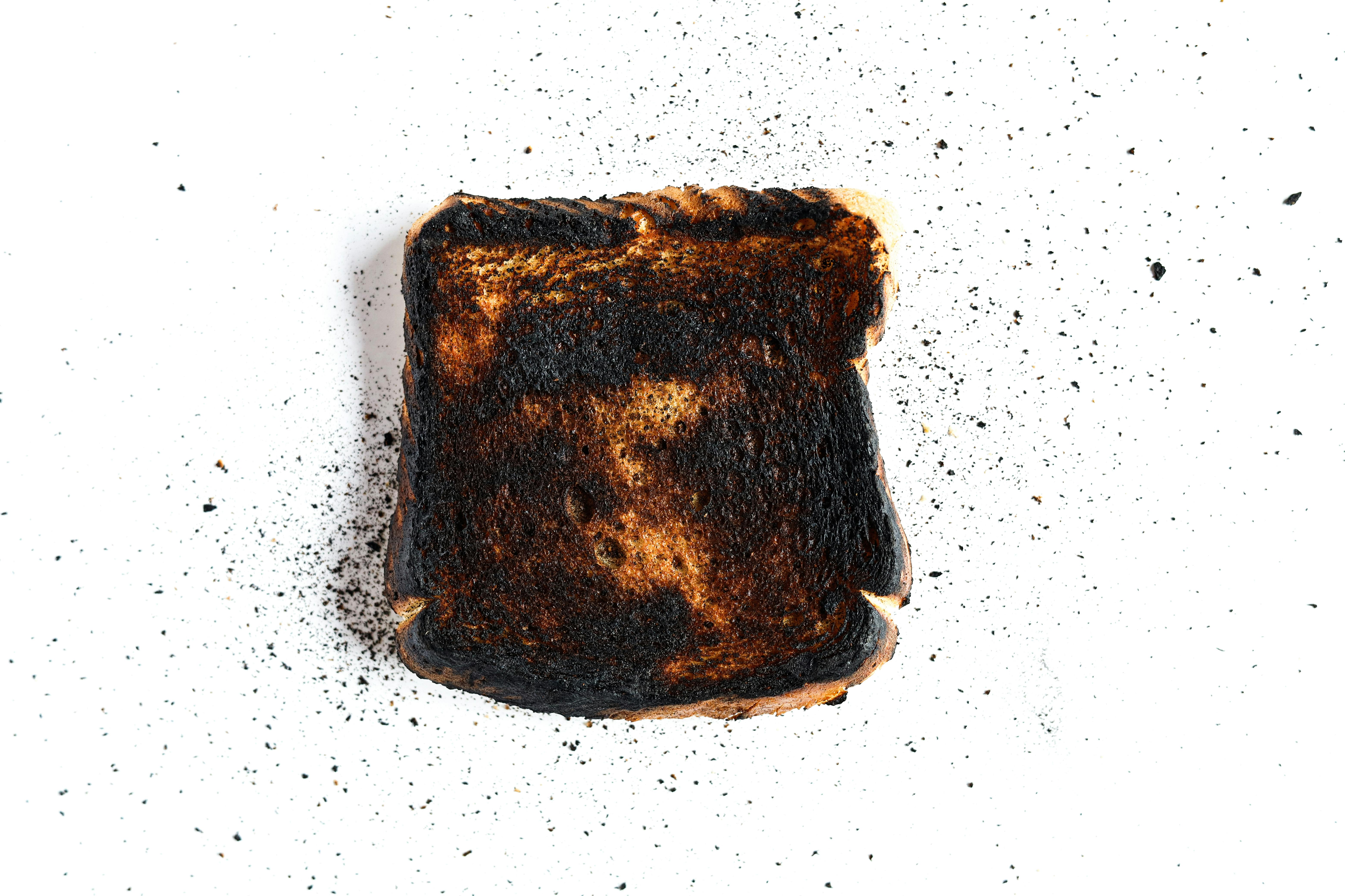 A piece of burnt toast on a white surface, perfect for culinary mishap concepts.