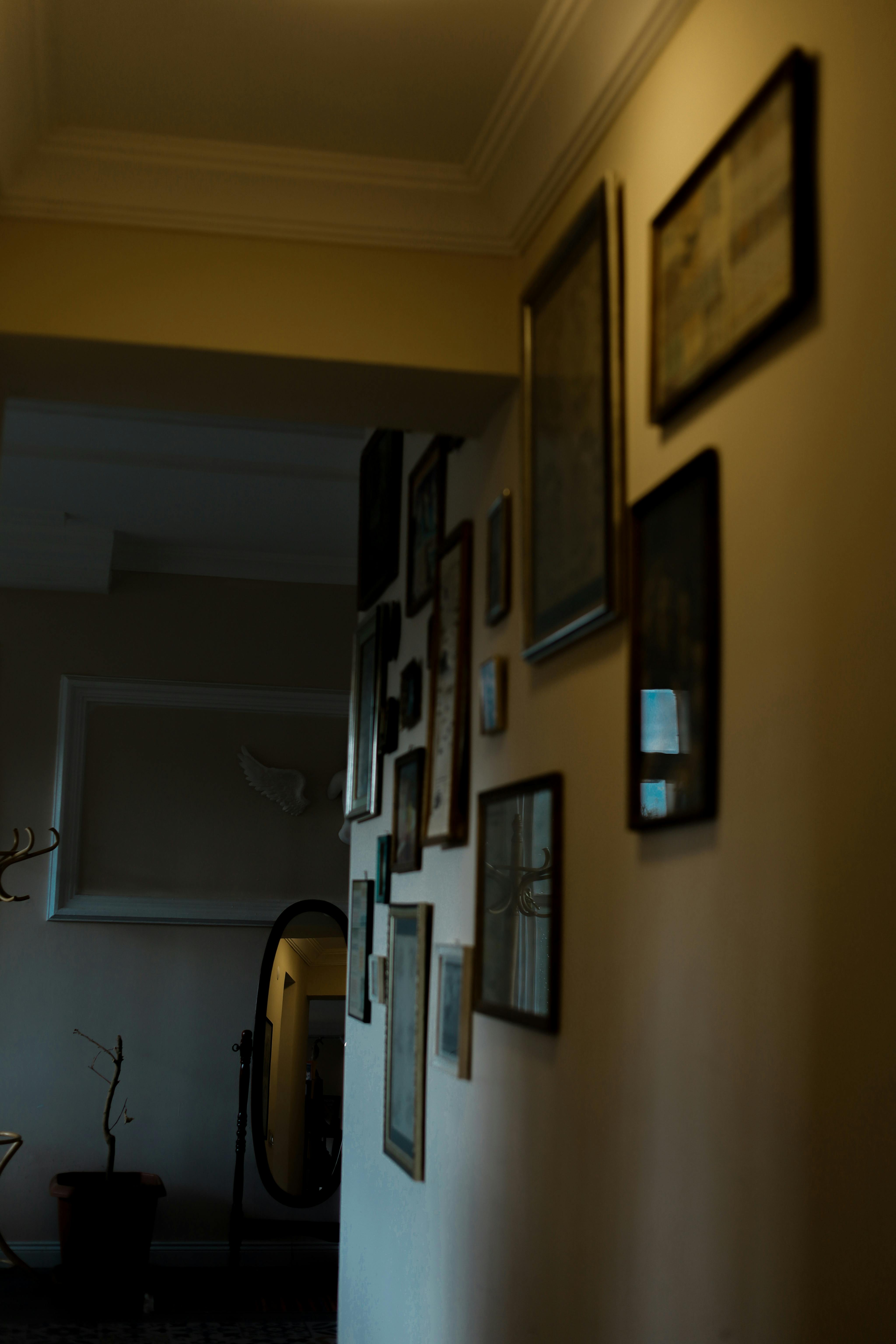 Dimly lit hallway filled with vintage framed art, creating a nostalgic and warm ambiance.