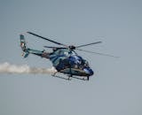 Blue Helicopter in Flight with Smoke Trail