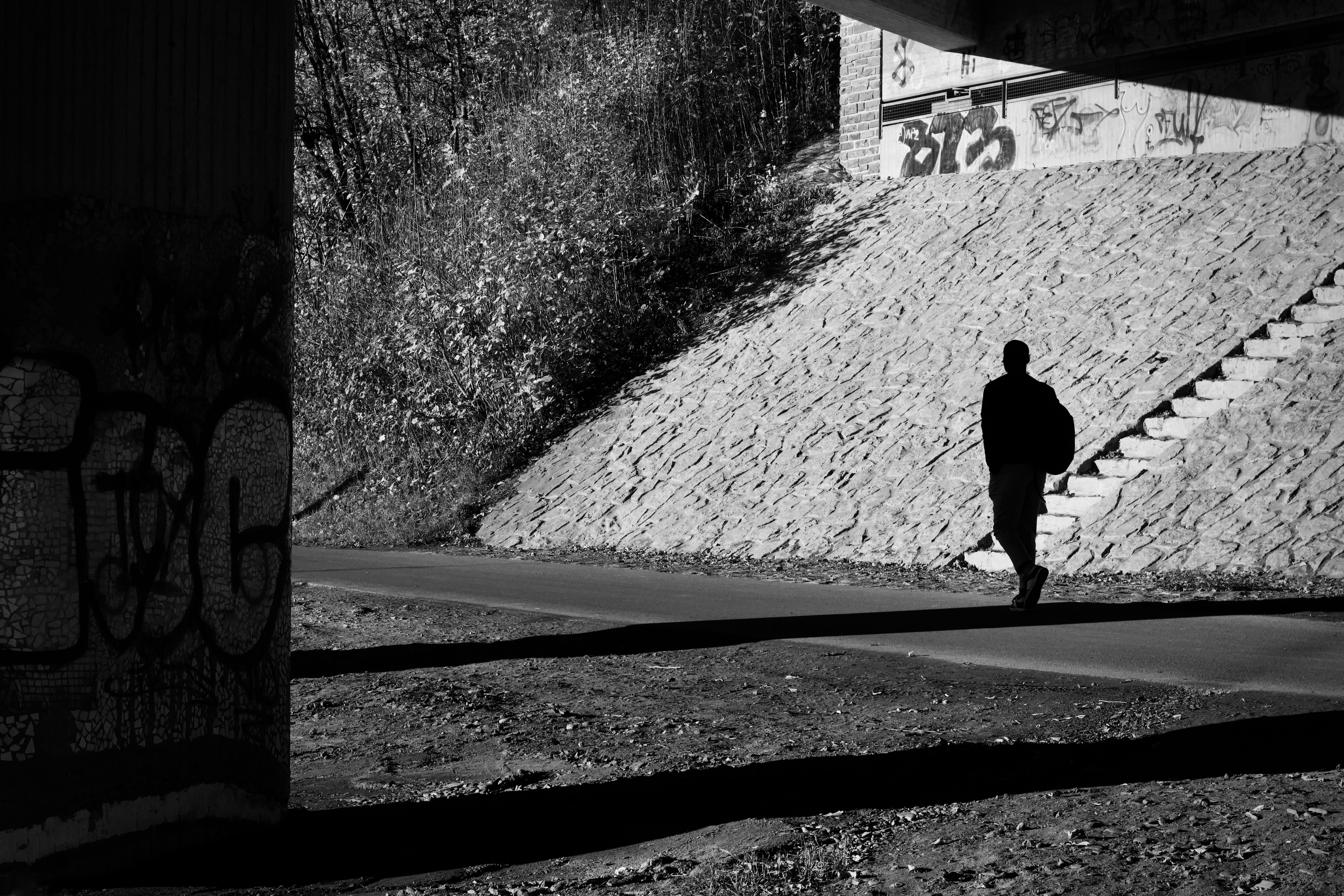 Silhouette of Man Walking Under Urban Bridge · Free Stock Photo