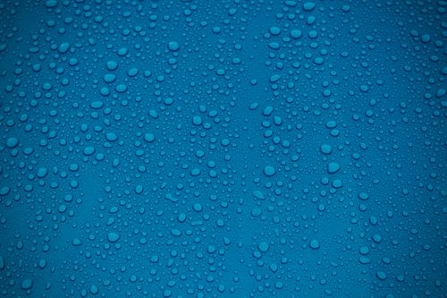 Free Close-up of a vibrant blue surface covered with water droplets, creating an abstract and refreshing pattern. Stock Photo