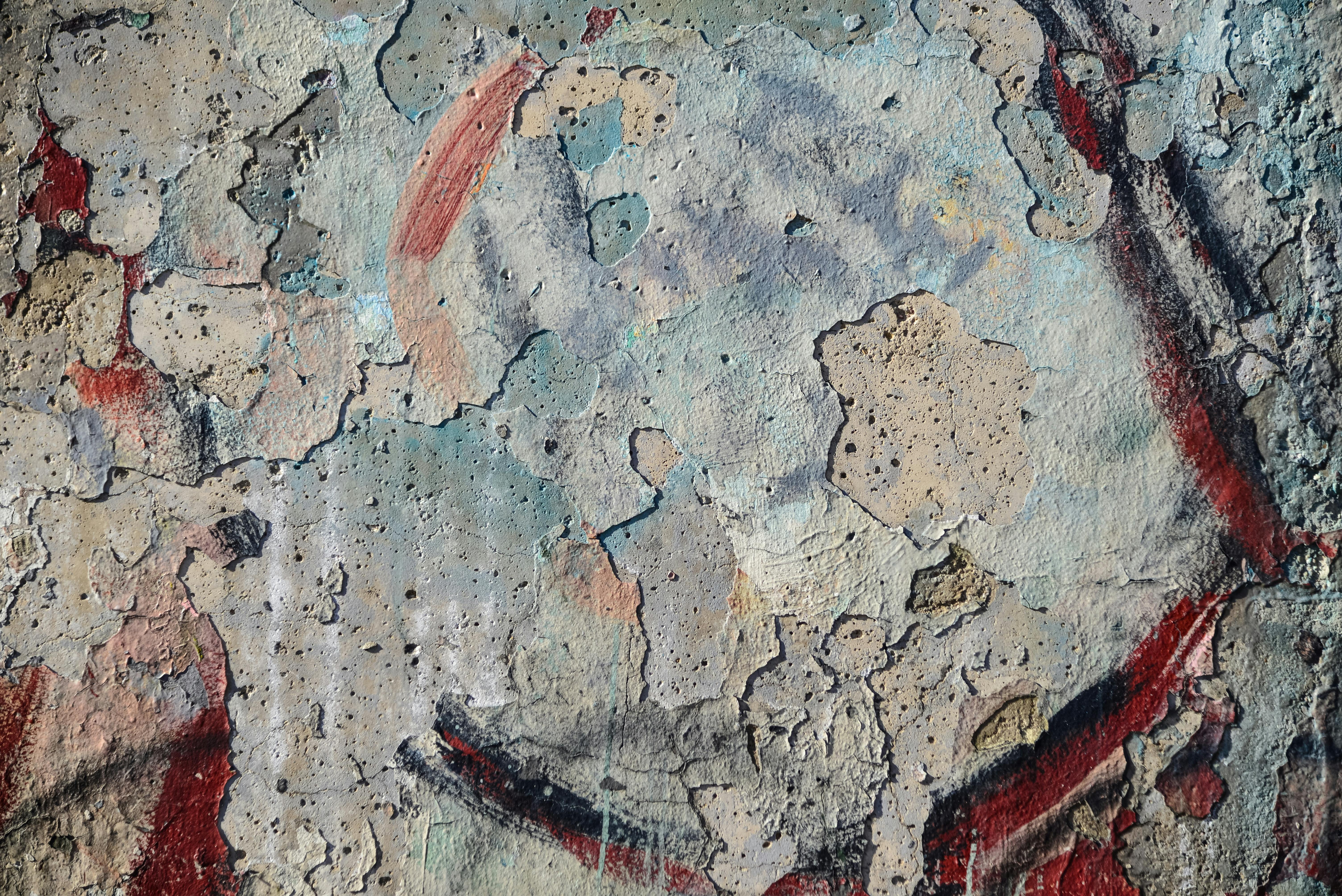 Close-up of a weathered wall with peeling paint and graffiti, showcasing urban decay and texture.