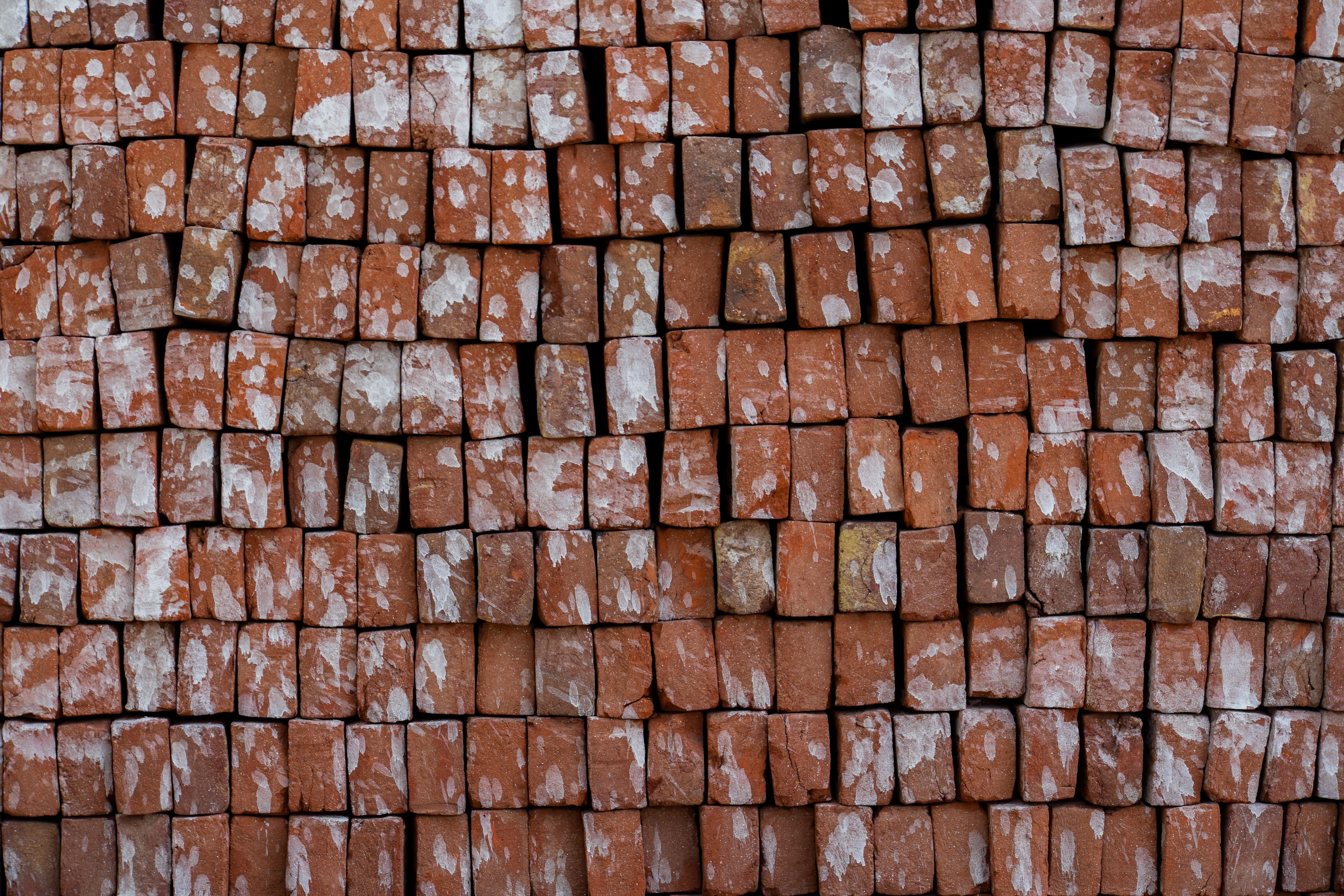 A detailed view of a wall made from stacked red clay bricks showing natural patterns.