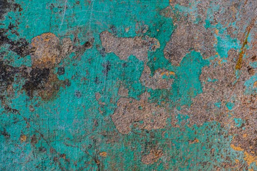 Close-up of a rustic, textured turquoise wall with peeling paint and patina details.