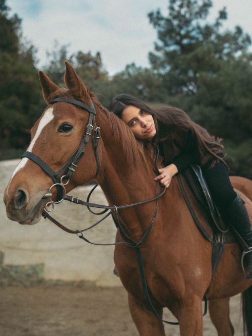 Free A woman rests on her brown horse outdoors, surrounded by nature, showcasing a serene moment of connection. Stock Photo