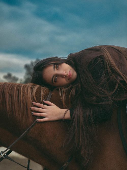 Free Serene portrait of a woman lying on a horse, capturing tranquility and connection with nature. Stock Photo