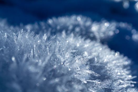 Detailed macro shot of frost crystals glistening in winter sunlight, showcasing intricate icy patterns.
