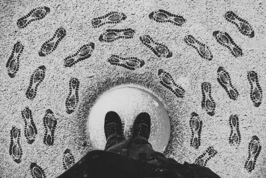 Artistic black and white photo of footprints forming a circle in the snow, with a central perspective view.