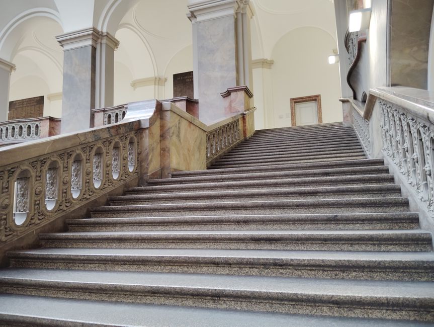 A grand marble staircase in a historic building, showcasing neoclassical architecture.