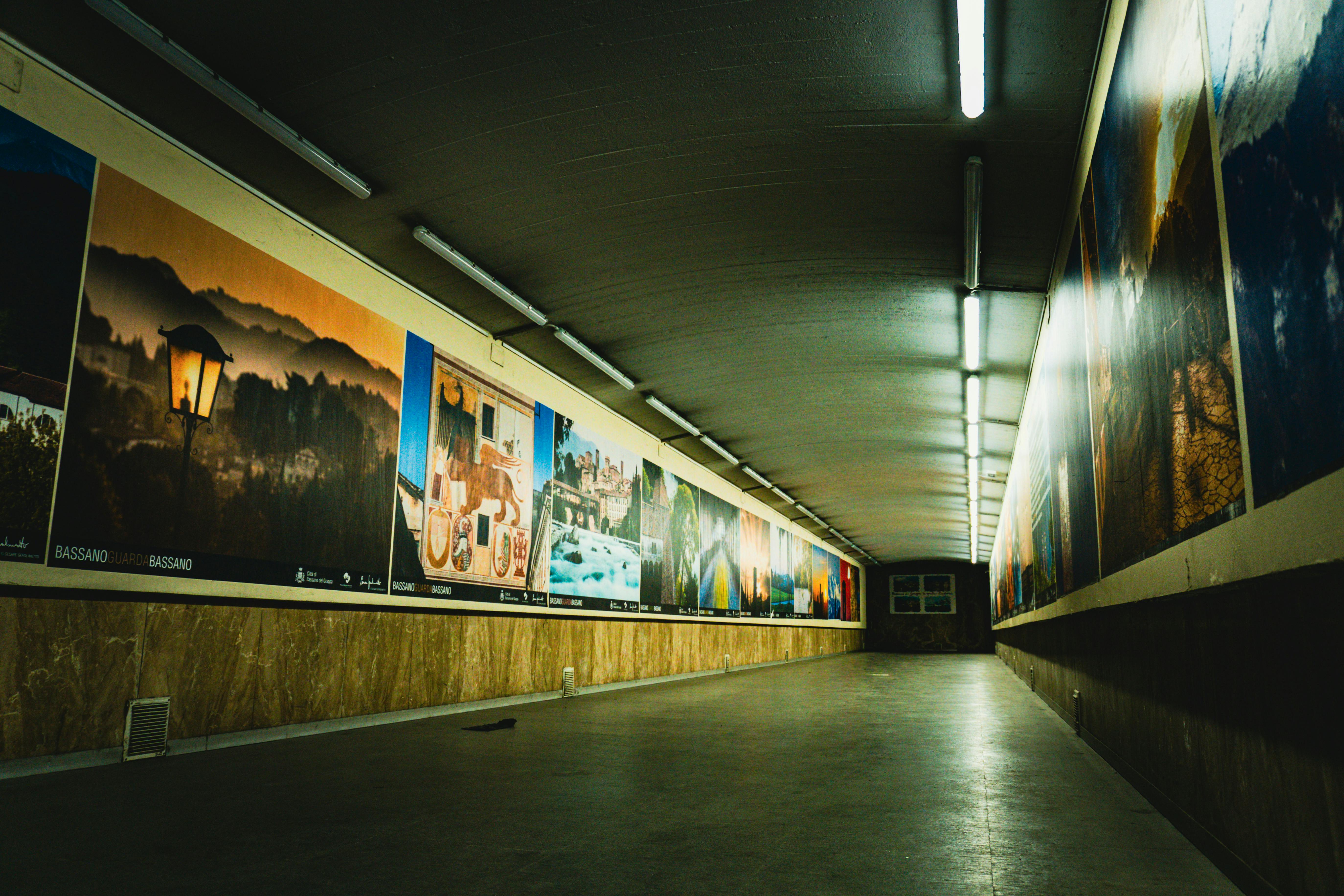 Zadarmo Dlhý, prázdny podzemný tunel zdobený veľkými zarámovanými umeleckými dielami na oboch stranách, osvetlený stropnými lampami. Fotka z fotobanky