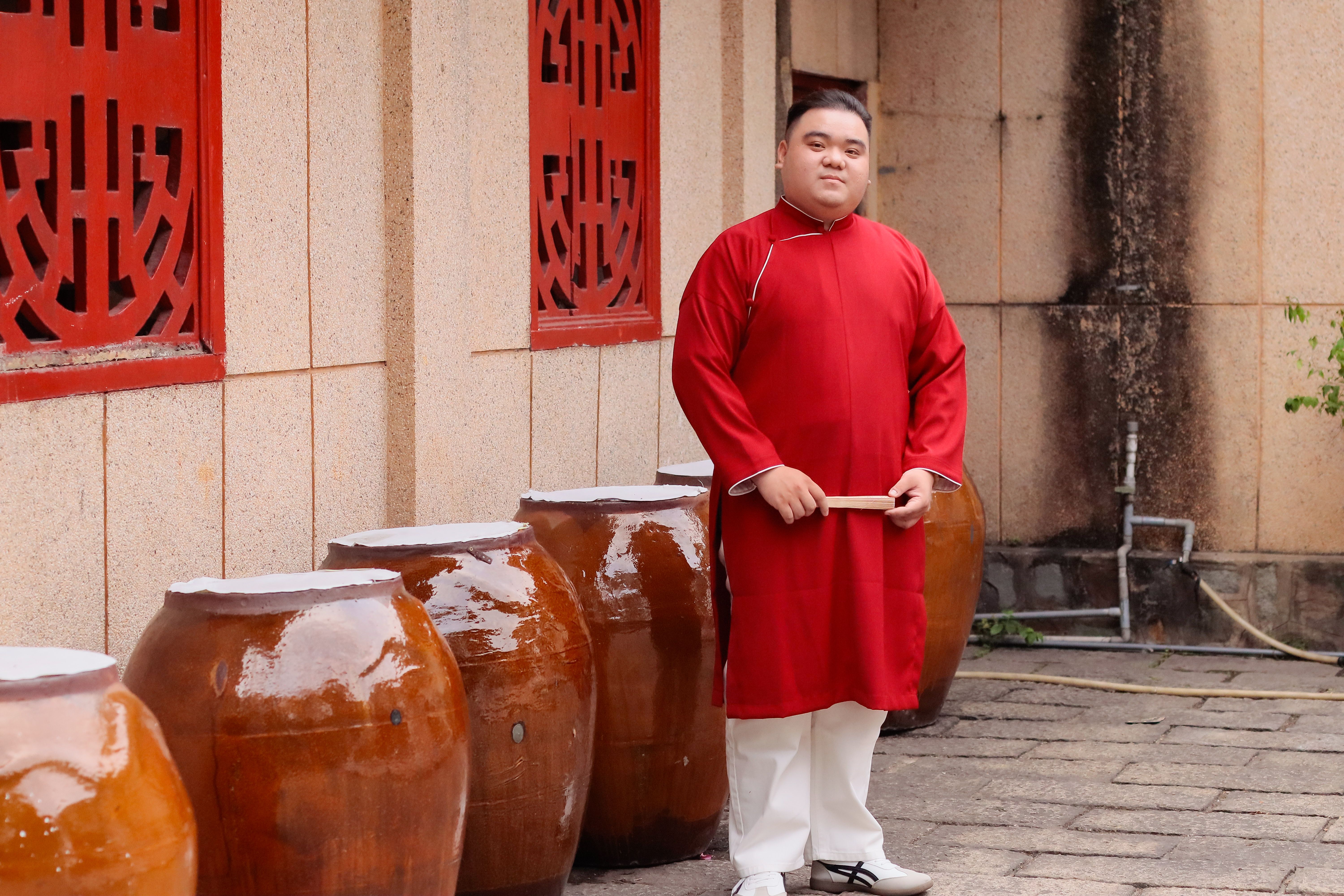 Hai con gà trống đứng trong khu vực đấu truyền thống, khán giả quan sát căng thẳng phía sau hàng rào