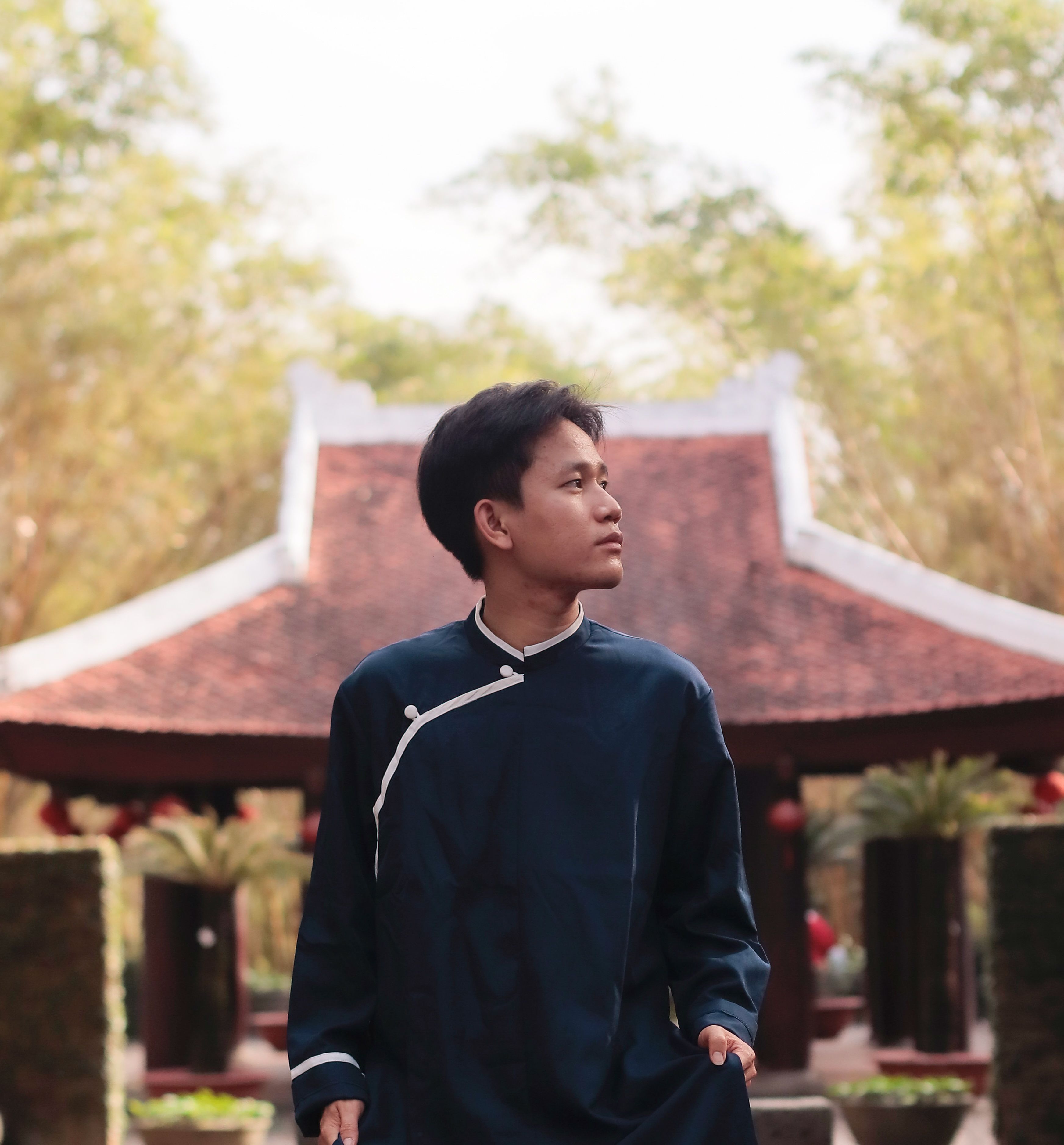 Portrait of a young man in traditional attire standing by a historic temple