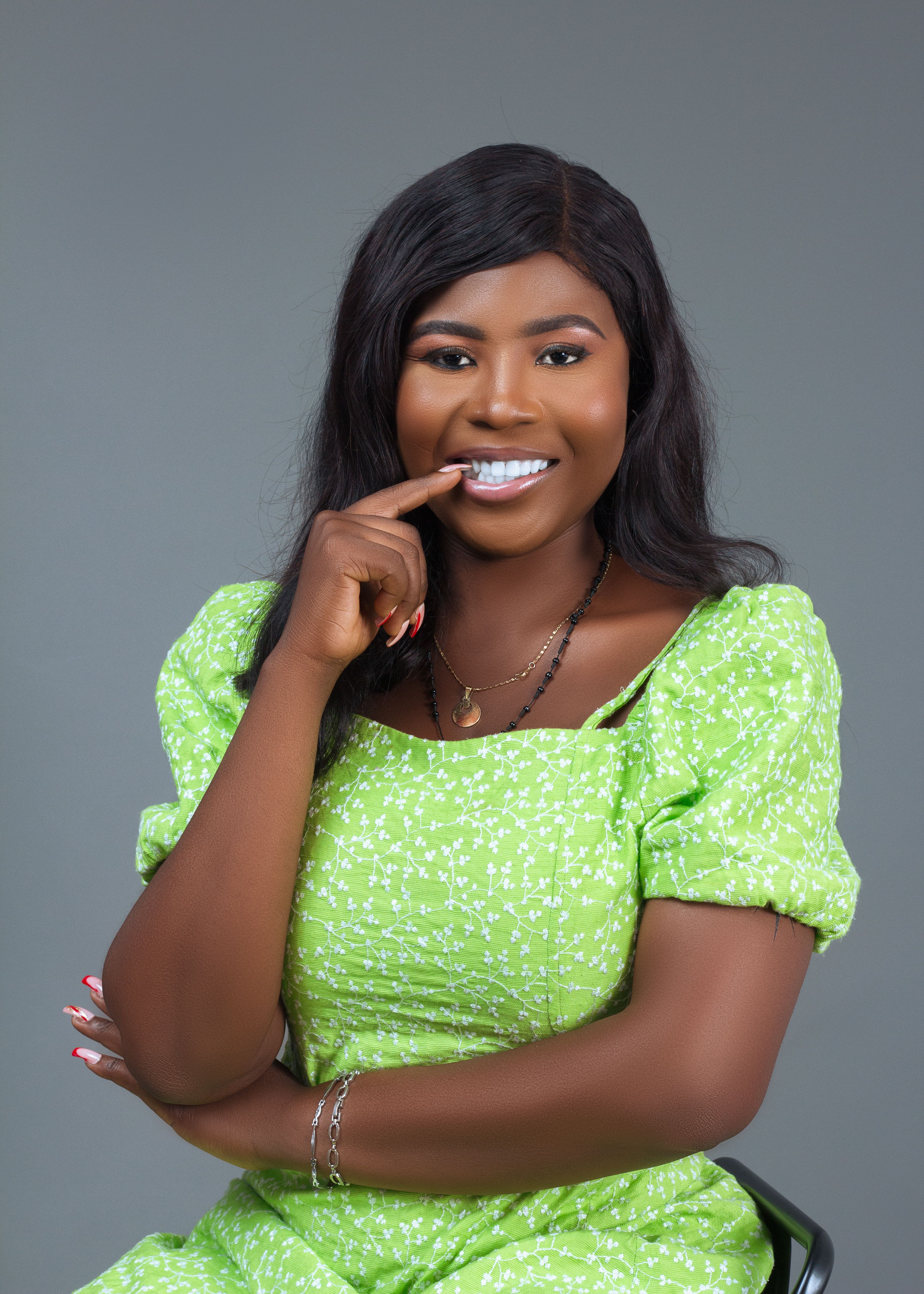 Confident woman in vibrant green dress posing elegantly with a thoughtful smile and hand gesture.