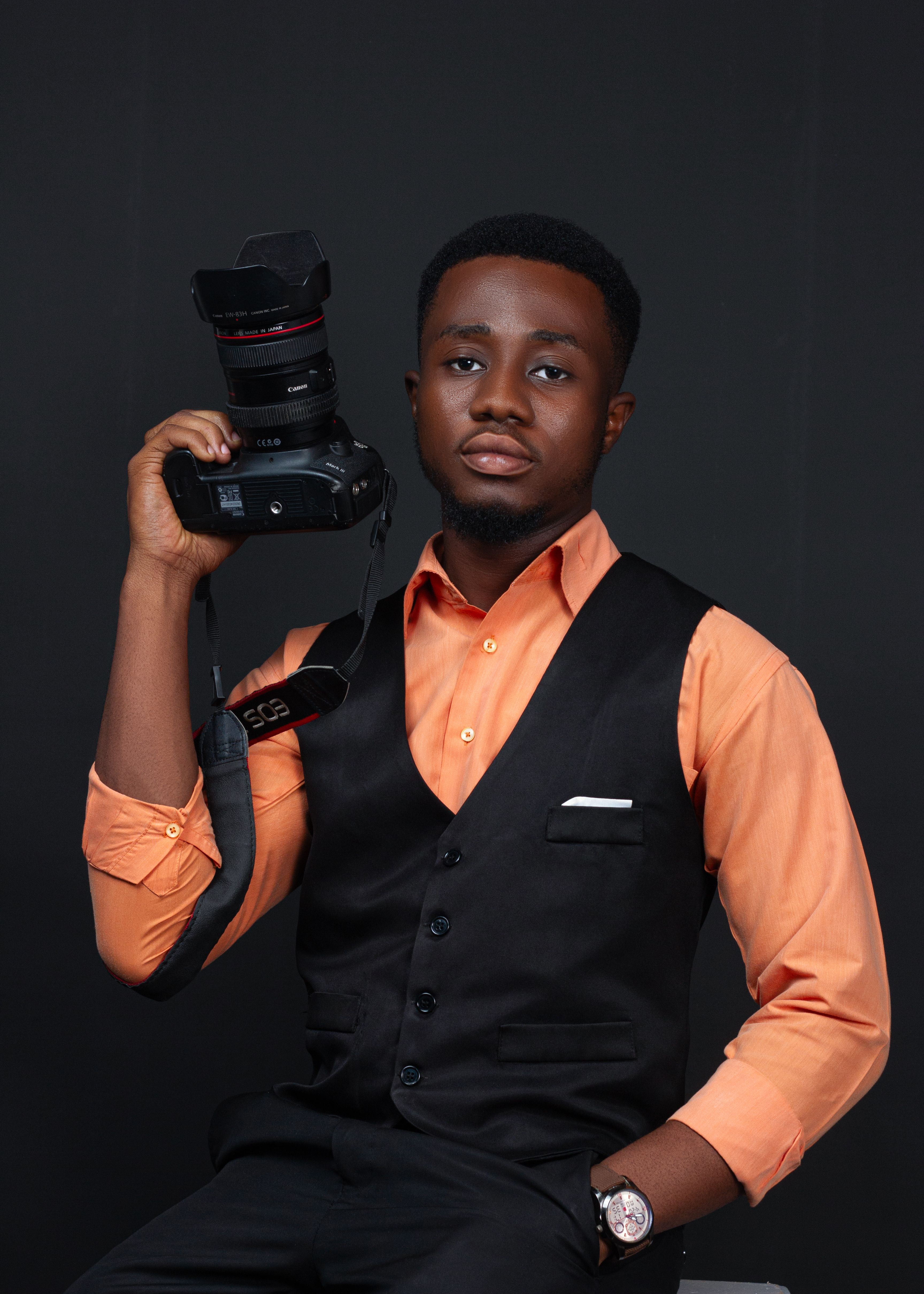 Confident male photographer holding DSLR camera, dressed in formal attire.