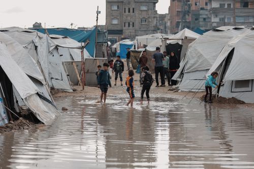 Free Children play in a flooded refugee camp in Gaza, reflecting resilience and daily life challenges. Stock Photo