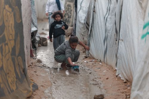 Free Children playing in muddy alley of a Gaza refugee camp, reflecting resilience and hardship. Stock Photo