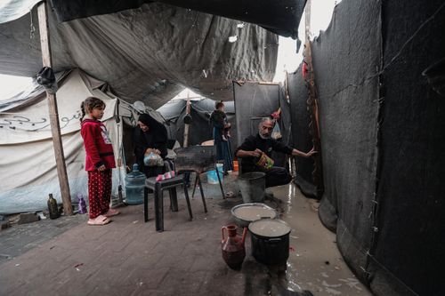 Free Family inside a makeshift tent in Gaza, depicting daily life challenges. Stock Photo