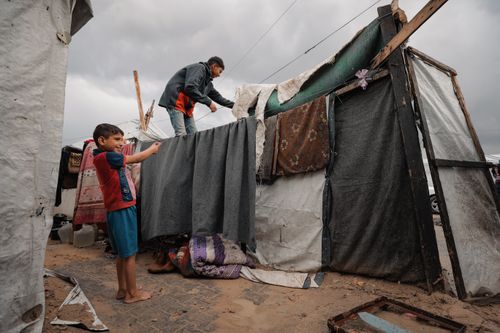 Free Children in a Gaza Strip refugee camp construct a makeshift shelter. A poignant scene of resilience. Stock Photo
