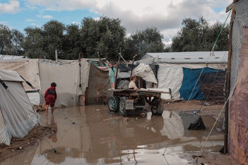 Free Children navigate a flooded refugee camp in Gaza, highlighting resilience amid challenging conditions. Stock Photo