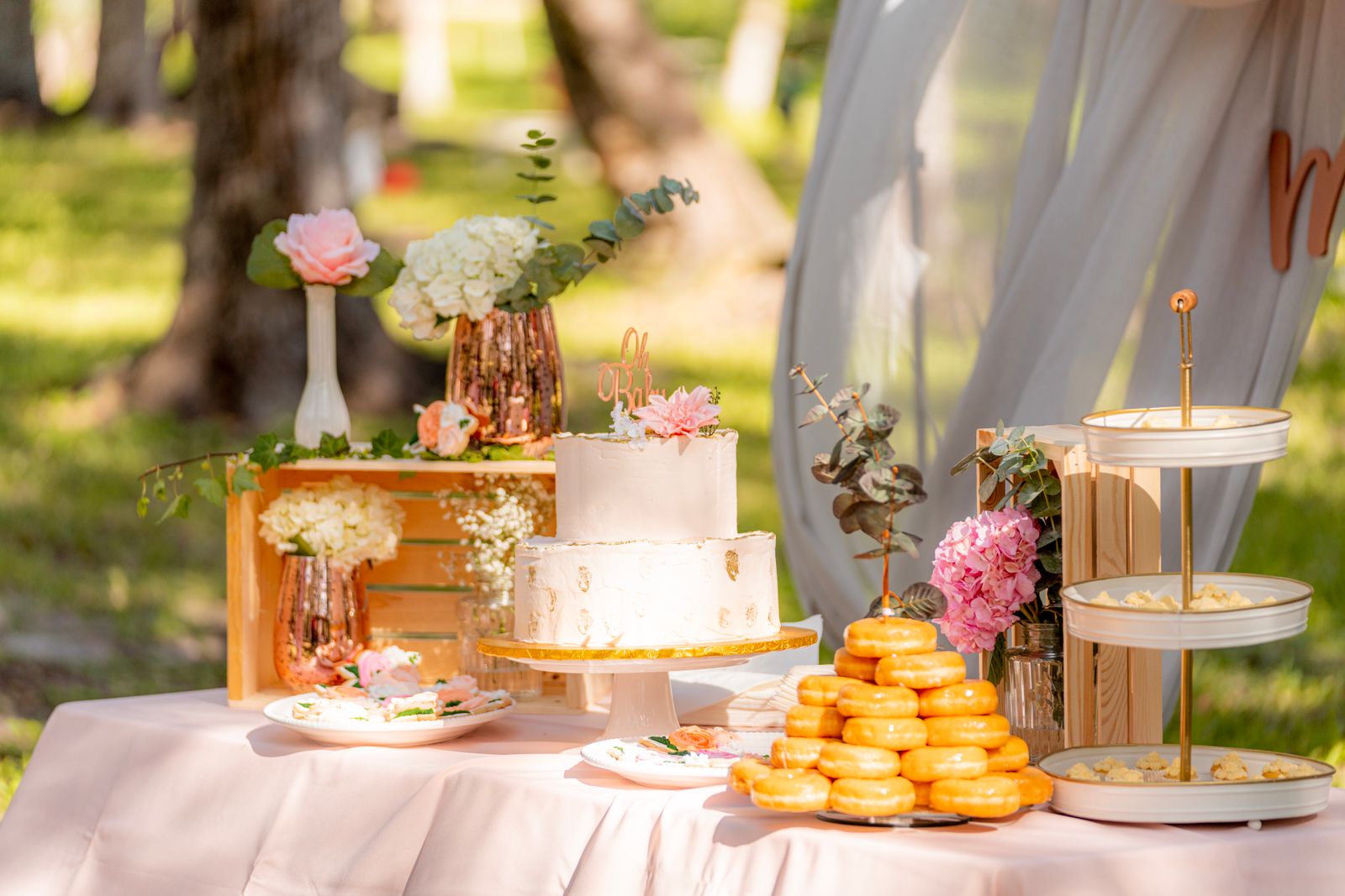 Outdoor wedding dessert table with cake and donuts
