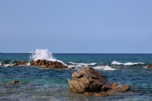 Free Waves crashing on rocky shore with clear sky, depicting serene seascape. Stock Photo