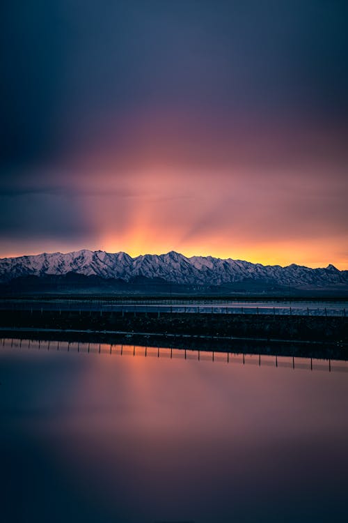 Sunset Over A Snow Covered Mountain Near Body of Water