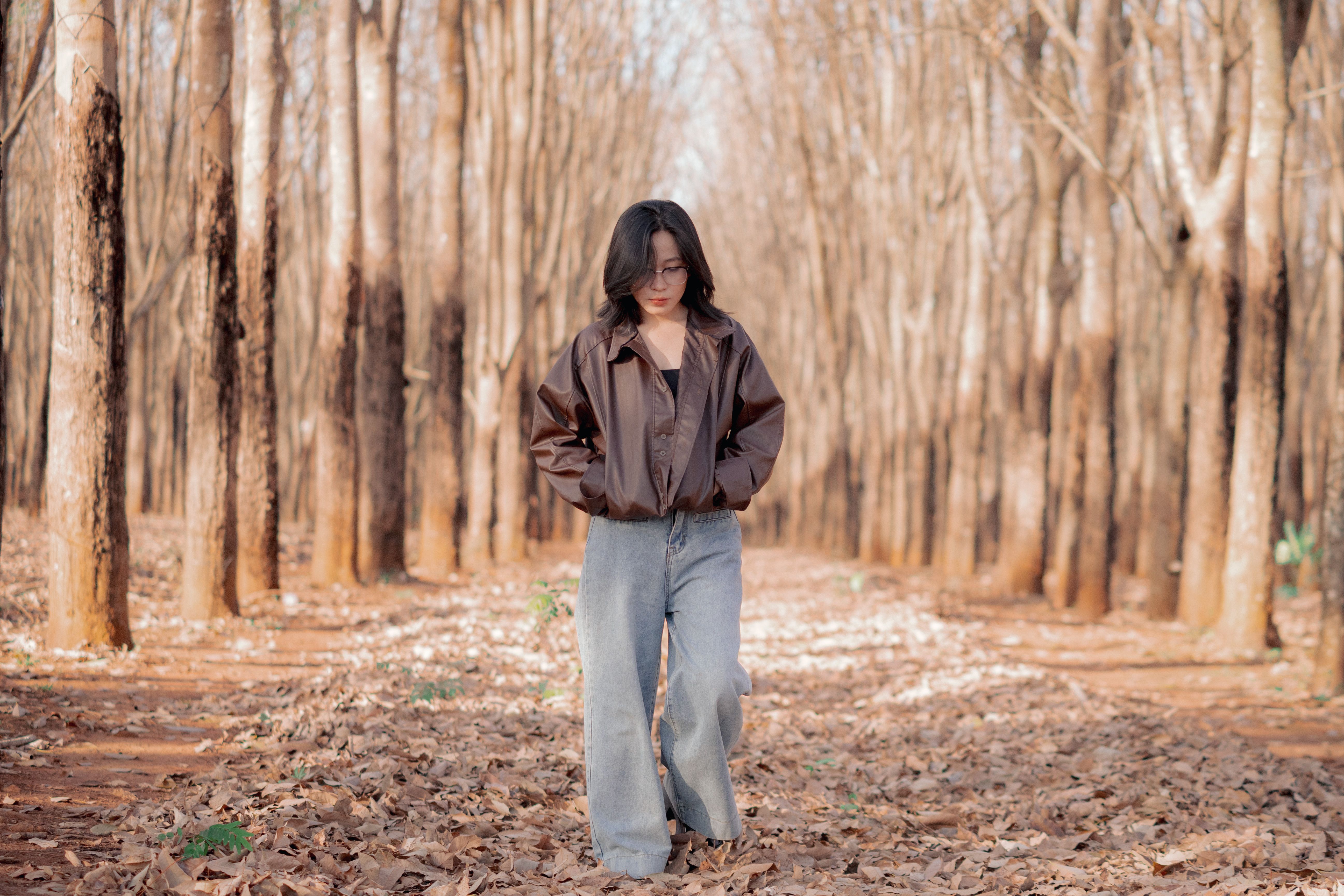 A woman strolls through a forest with fallen leaves, capturing the essence of autumn in Vietnam.