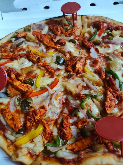 Free Delicious spicy chicken pizza topped with colorful peppers and melted cheese in a pizza box. Stock Photo