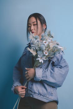 这幅肖像画描绘了一位手持精致花束的女子，背景是柔和的蓝色，画面宁静