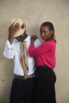 Fashionable couple posing with stylish attire indoors against a textured wall background.