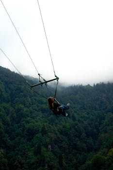 Person swings over lush Rize forest, offering a thrilling adventure in nature.