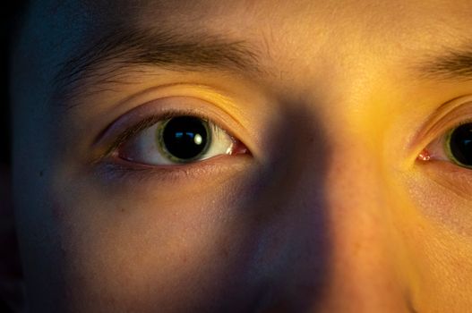 A detail-oriented and intimate close-up photo of a young person's eyes with interesting lighting effects.