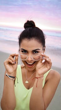 日落时分，一位快乐的女士在宁静的海滩上微笑着调整眼镜