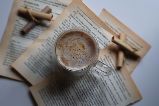 Cozy cup of coffee surrounded by vintage book pages and scrolls for a nostalgic feel.