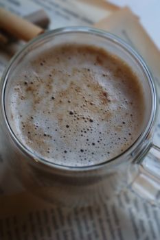 Close-up of a frothy cappuccino on vintage paper background, exuding warmth and coziness.