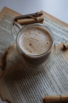 A serene flat lay of a frothy coffee cup surrounded by aged papers and tied scrolls.