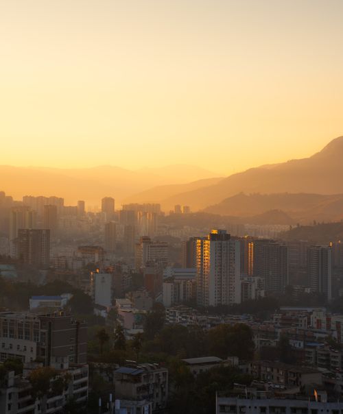 Free A stunning sunrise illuminates a city skyline against the backdrop of mountains, creating a warm, dramatic scene. Stock Photo