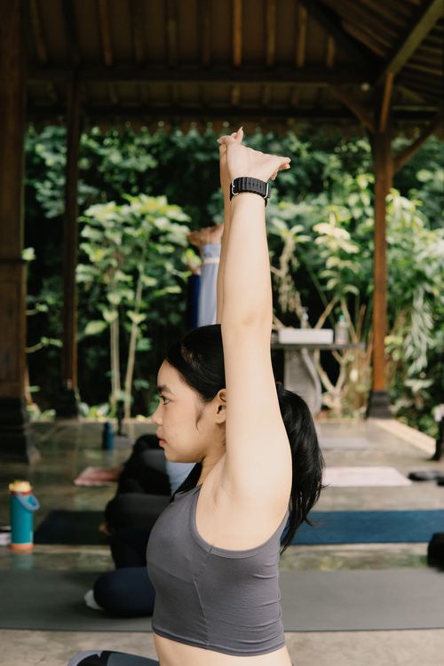 Free A woman practicing yoga in an outdoor pavilion surrounded by lush greenery. Stock Photo