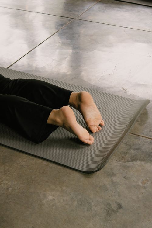 Free Feet on a gray yoga mat during an indoor yoga session, focused on simplicity. Stock Photo