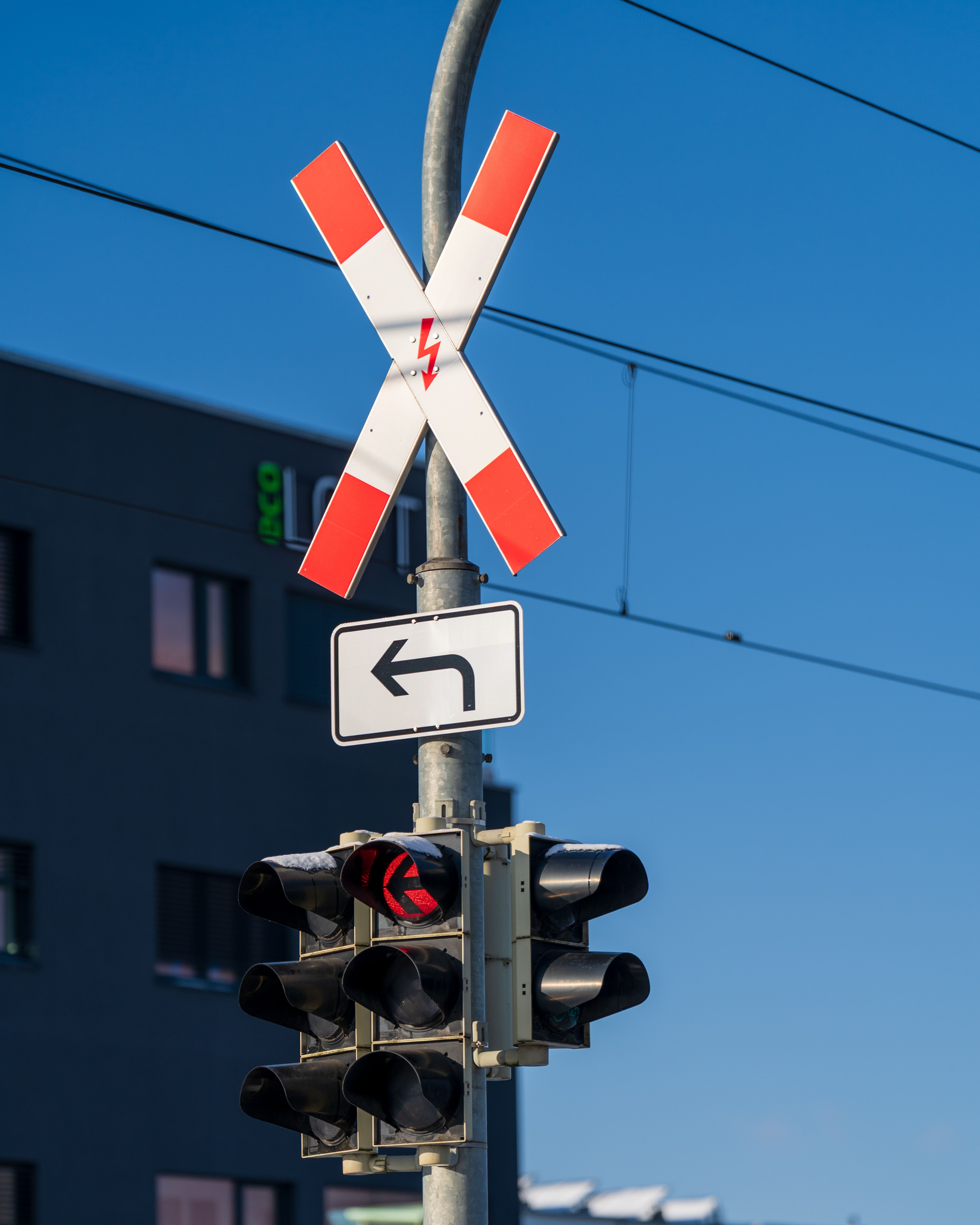 Intersection with railway crossing sign, traffic lights, and blue sky.