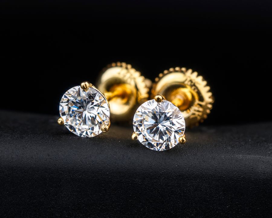 Gold and diamond stud earrings on a black surface