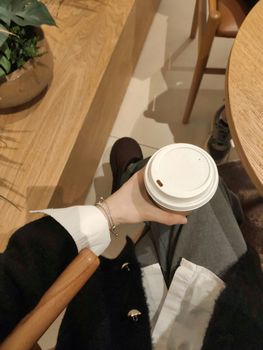 Elegant scene of a person holding a coffee cup in a cozy modern cafe, capturing a warm moment.