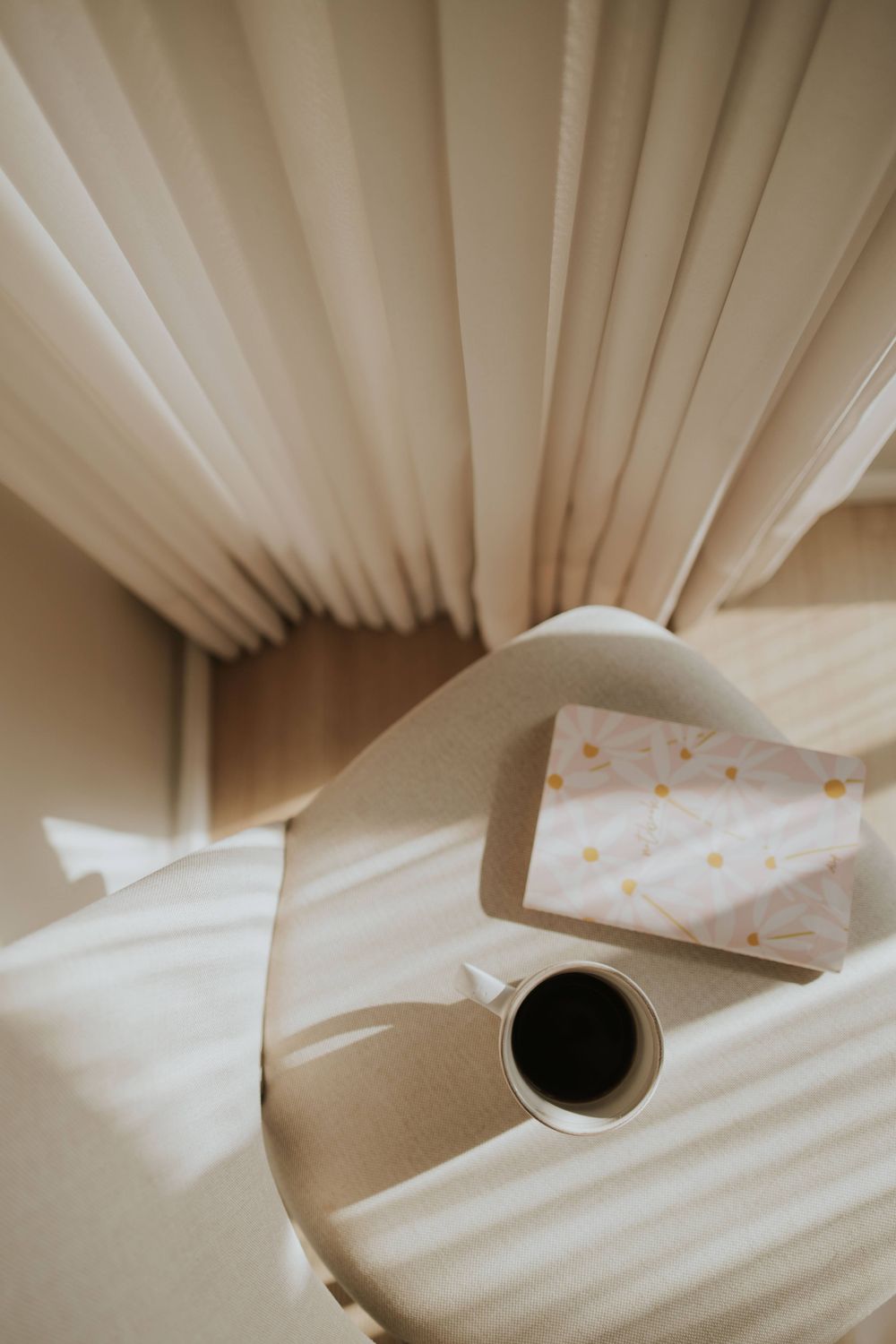 Café e livro sobre uma mesa iluminada pelo sol