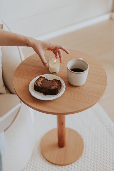 A cozy indoor setup with coffee, cake, and a candle on a wooden table.