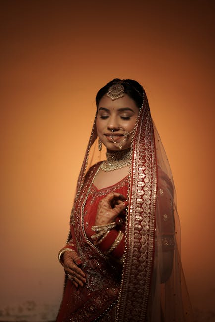 South Asian bride in red bridal lehenga with intricate henna designs, looking serene.