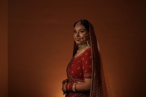 Free A beautiful Indian bride in traditional red lehenga and jewelry, posing gracefully. Stock Photo