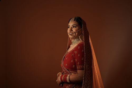 Free Traditional Indian bride in red attire with intricate jewelry, side view portrait. Stock Photo